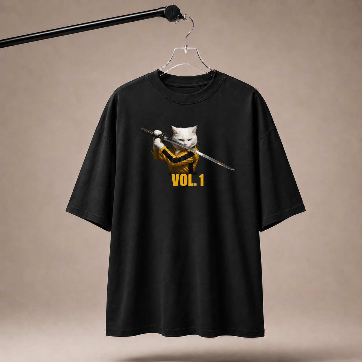 Black t-shirt with a graphic of a cat holding a sword and 'VOL. 1' text on a beige background