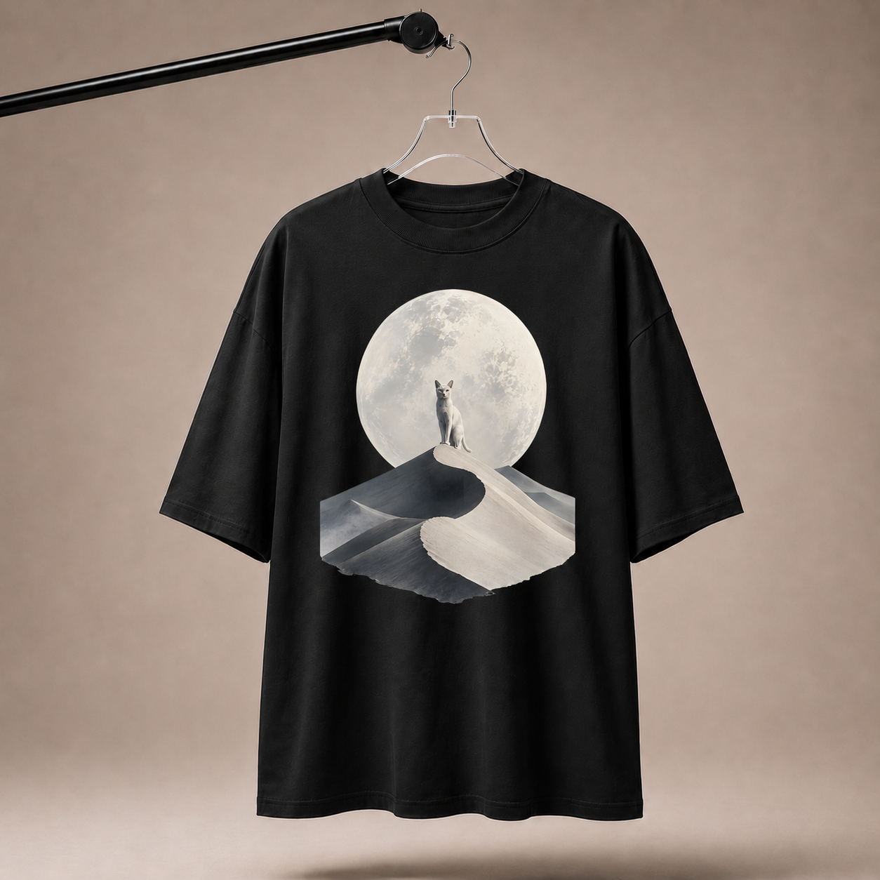 Black t-shirt with a graphic design of a cat standing on a moonlit path, hanging on a beige background.
