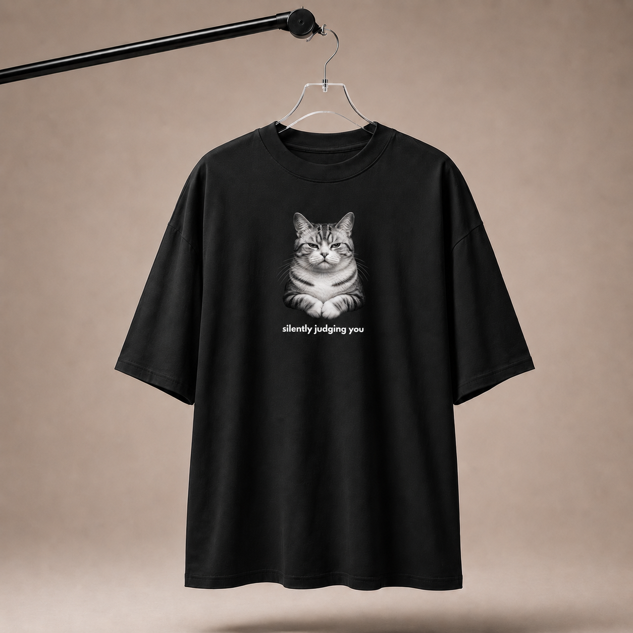 Black t-shirt with a cat graphic and text 'silently judging you' on a beige background