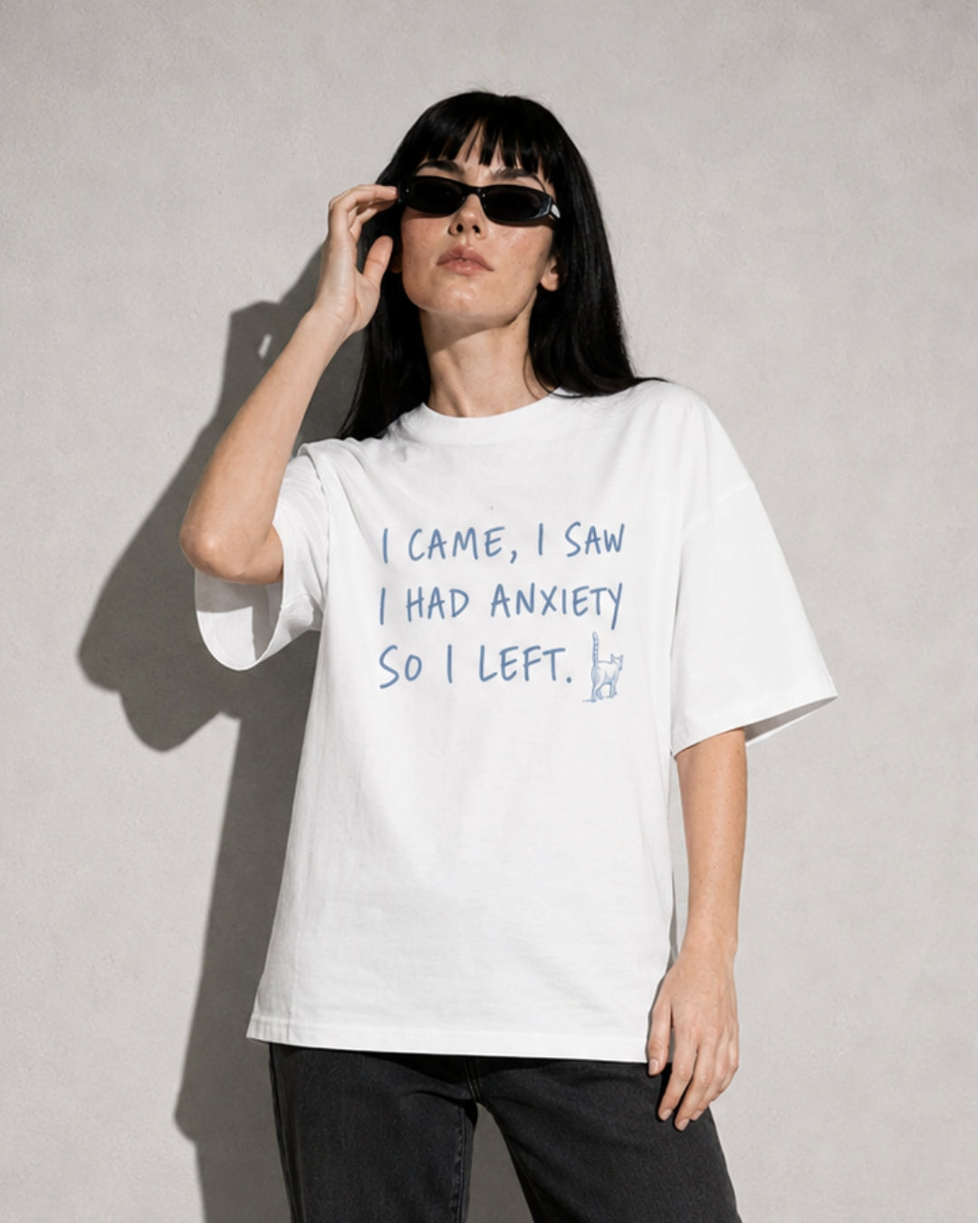 Person wearing a white t-shirt with text, standing against a plain background