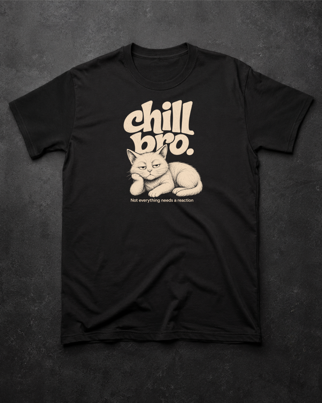 A black short-sleeve t-shirt laid flat on a dark textured background, featuring a beige graphic of a sleeping cat with the text 'chill bro.' and 'not everything needs a leash.
