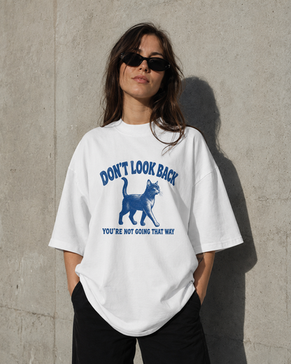 Person wearing a white t-shirt with a graphic and text against a concrete wall.