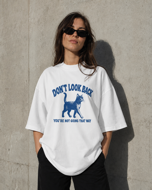 Person wearing a white t-shirt with a graphic and text against a concrete wall.