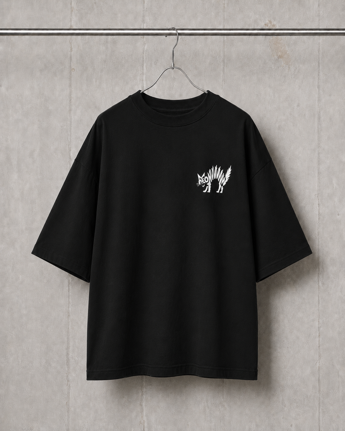 Black t-shirt with a white graphic on a hanger against a gray concrete wall