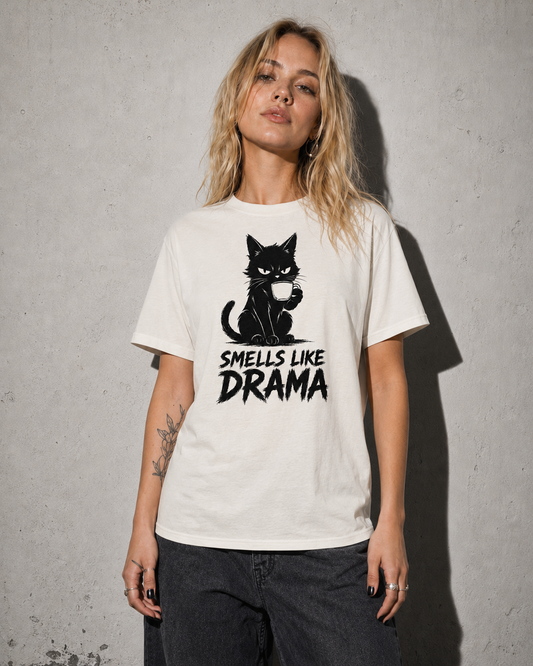 Person wearing a white t-shirt with a black cat graphic and text 'SMELLS LIKE DRAMA' against a gray background