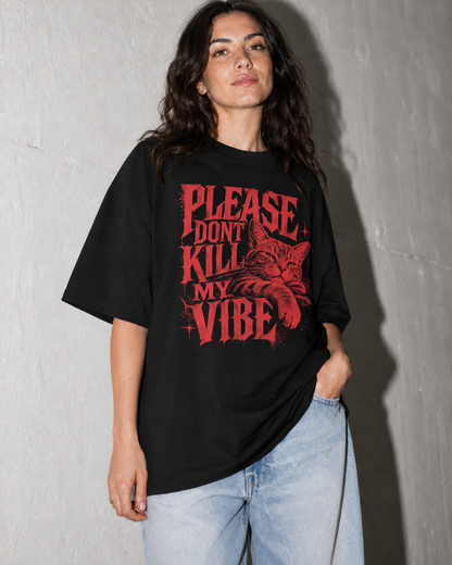 Person wearing a black t-shirt with red text and graphics against a gray wall.